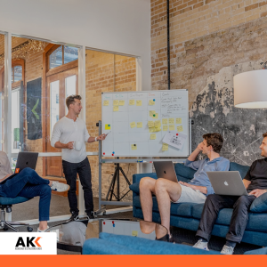 Zespół pracujący przy tablicy projektowej i laptopach, symbolizujący analizę danych i modelowanie finansowe.