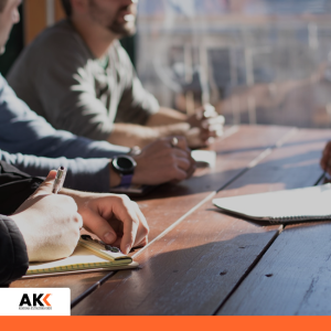 Osoby robiące notatki podczas spotkania biznesowego, symbolizujące analizę transakcji i dokumentacji podatkowej.