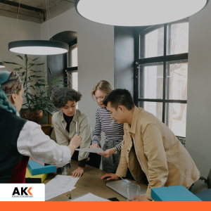 Zespół pracowników biurowych współpracujący nad wspólnym projektem komunikacyjnym – Akademia Kształcenia Kadr.