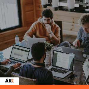 Grupa młodych ludzi pracuje przy laptopach przy wspólnym stole – szkolenie Podatek VAT 2026 w praktyce od KSeF przez nowe JPK