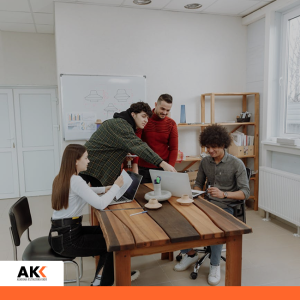 Czteroosobowy zespół pracuje przy laptopach w jasnej sali szkoleniowej przy tablicy – szkolenie Kompetencje cyfrowe AI dla sektora edukacji