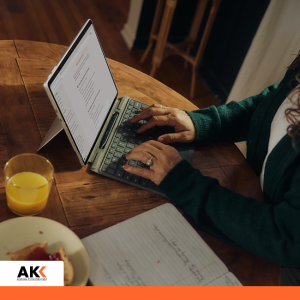 Osoba pracująca przy laptopie z notatkami, symbolizująca wykorzystanie narzędzi cyfrowych i AI w pracy biurowej.