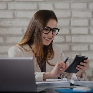 Kobieta pracująca przy biurku z kalkulatorem – profesjonalne szkolenia księgowe w Akademii Kształcenia Kadr.