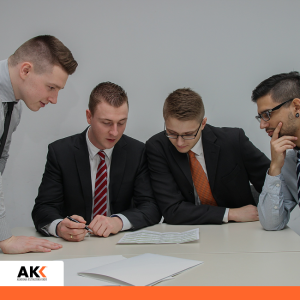 Czterech mężczyzn w garniturach analizuje dokumenty przy stole – szkolenie Controlling personalny