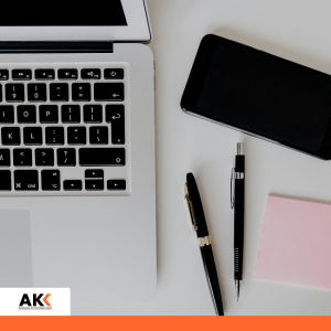 Laptop, smartfon, długopisy i różowa karteczka na białym biurku – szkolenie Prawo Pracy 2026 Karpacz